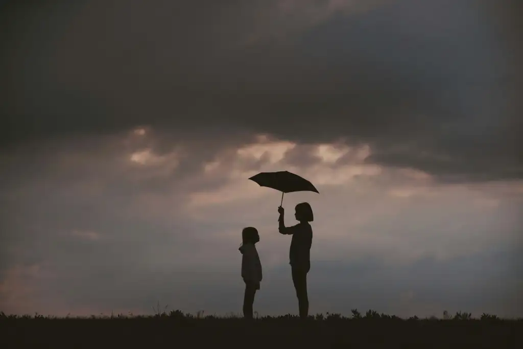 a woman holding an umbrella and a child standing in a field